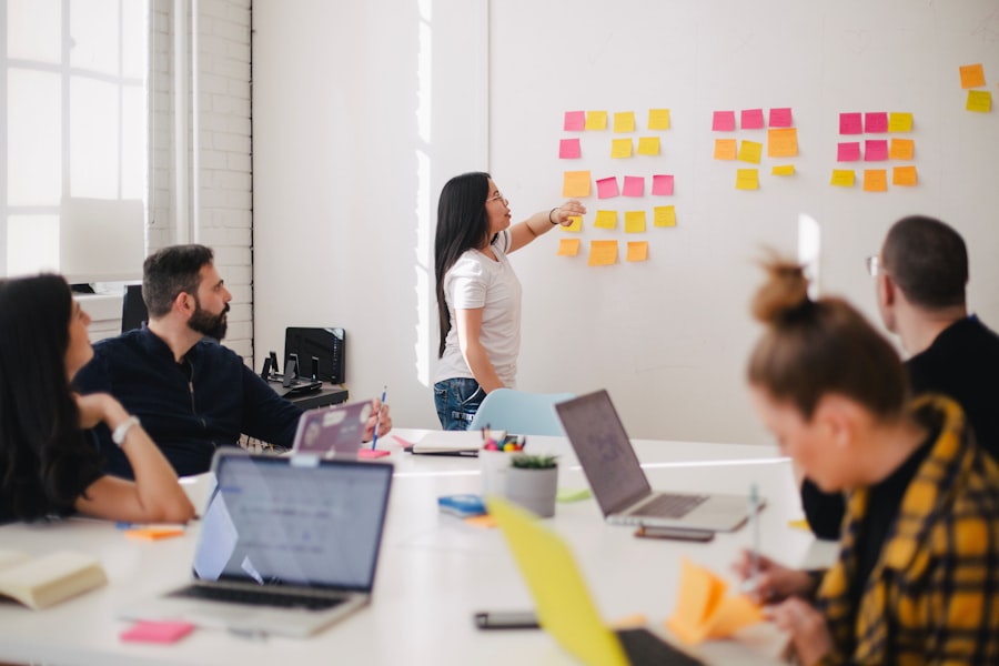 Business owner mapping a workflow on a wall of sticky notes while her team looks on