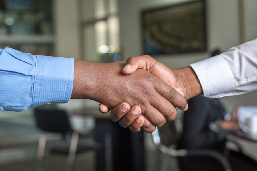 Two people shaking hands across an office table