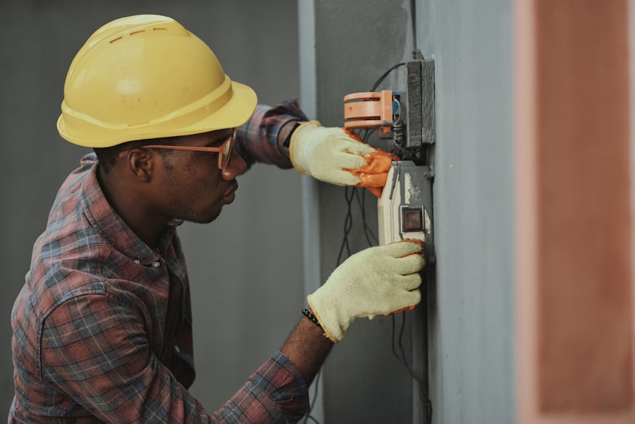 Electrician in a hard hat and safety glasses wiring equipment on a job site